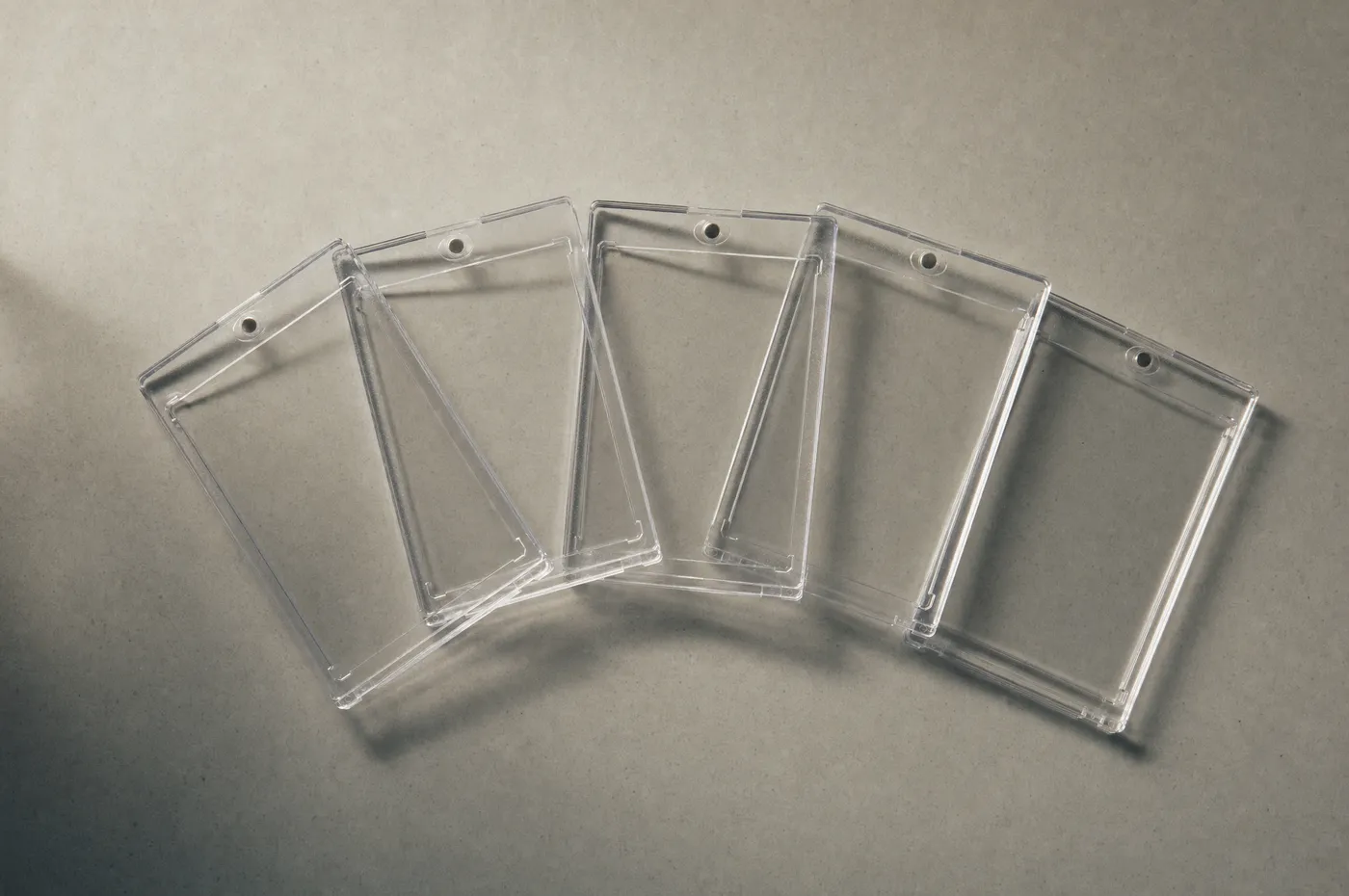 Protective trading card slabs fanned across a clean neutral surface